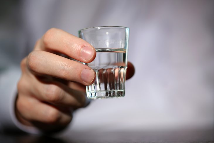 Man hand with glass of vodka , close up